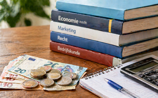 Foto: Geld, studieboeken, rekenmachine op tafel
