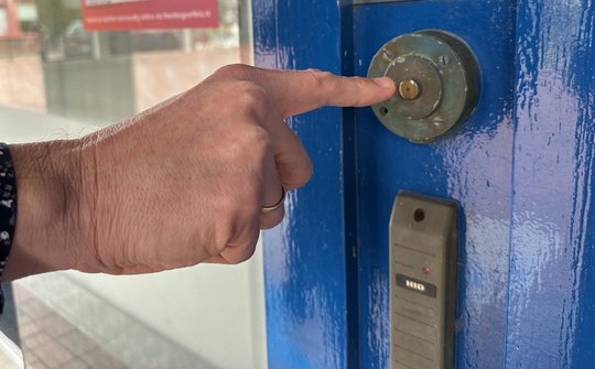Foto: Hand met vinger naar de deurbel