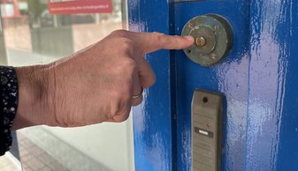 Foto: Hand met vinger naar de deurbel