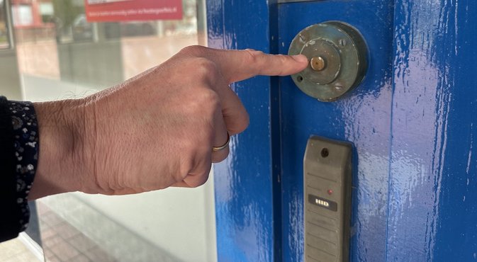 Foto: Hand met vinger naar de deurbel