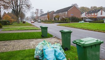 Containers en afvalzakken langs de kant van de weg