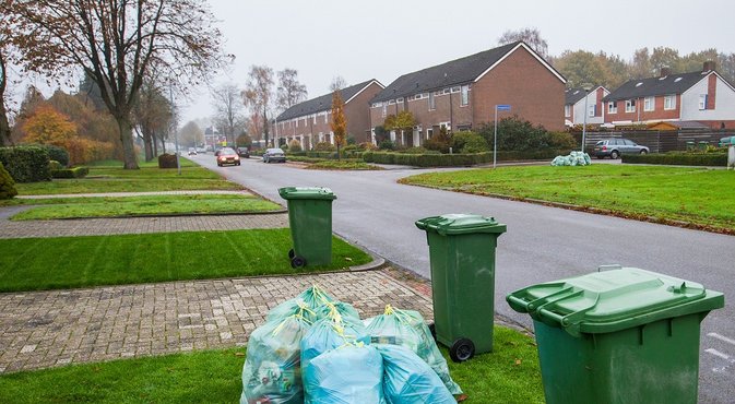 Containers en afvalzakken langs de kant van de weg