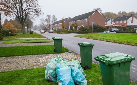 Containers en afvalzakken langs de kant van de weg