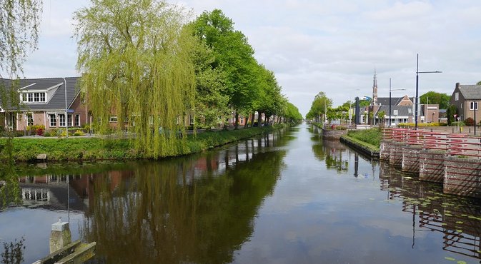 Foto Het kanaal tot in de verte met aan weerskanten huizen en bomen