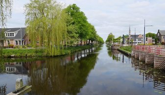 Foto Het kanaal tot in de verte met aan weerskanten huizen en bomen