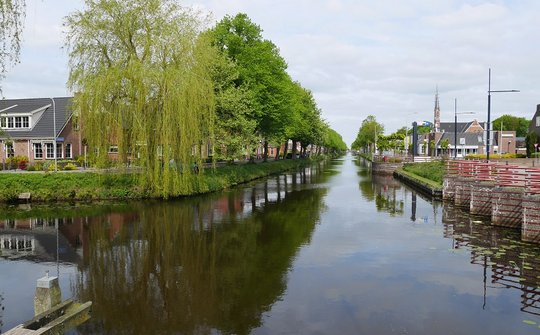 Foto Het kanaal tot in de verte met aan weerskanten huizen en bomen