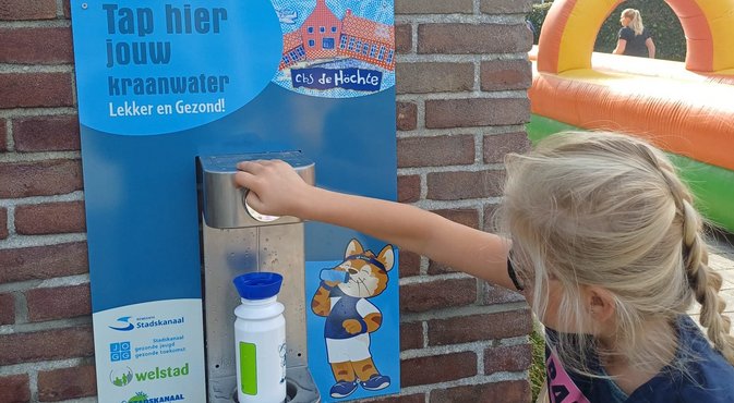 Foto: meisje die met de watertap haar bidon vult